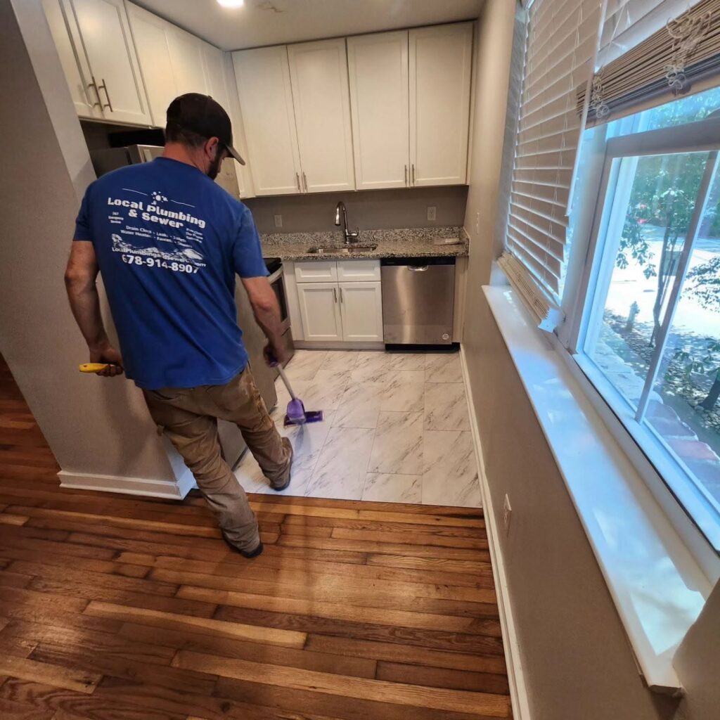 Local Plumbing & Sewer technician finishing a kitchen plumbing job