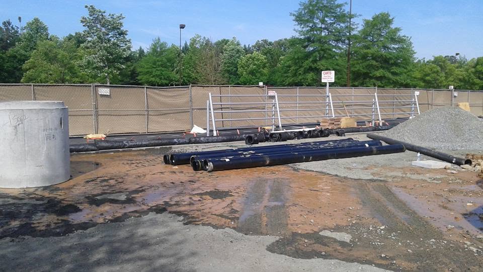 Commercial plumbing job site with a precast concrete structure and new pipe staged
