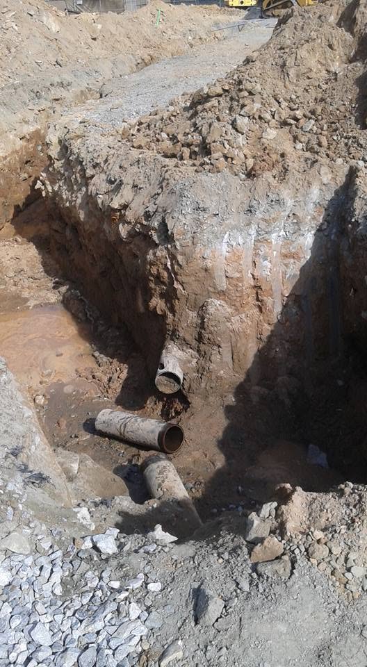 Deep excavation exposing underground pipe during a plumbing repair